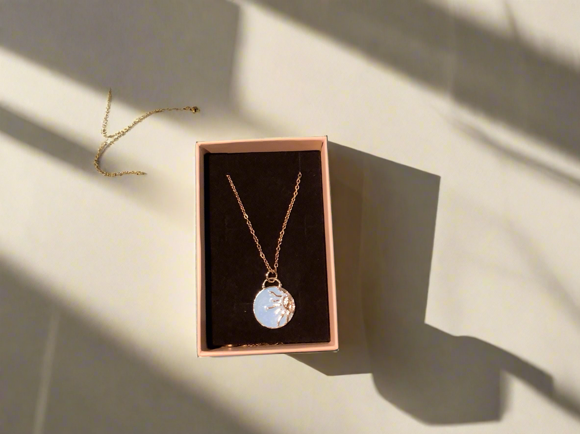 Necklace with enamel pale blue sun charm on a gold chain