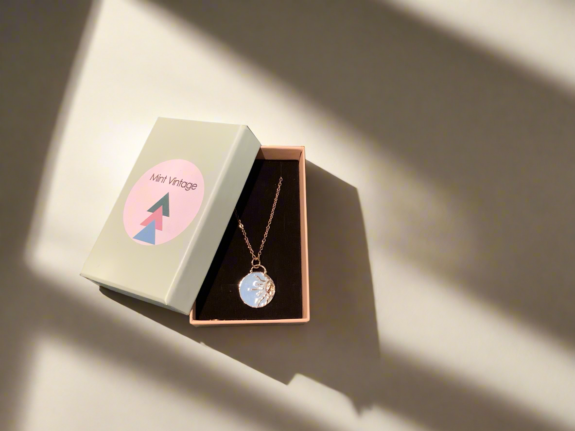 Necklace with enamel pale blue sun charm on a gold chain